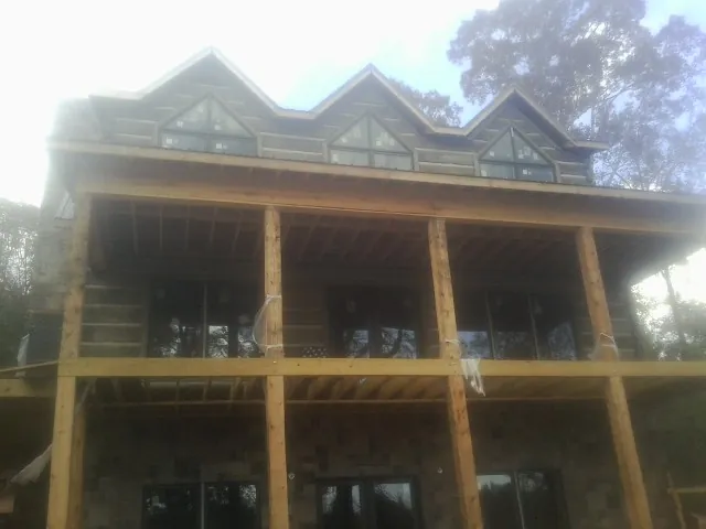 Dormers and porch framing on a large log home under construction — Roof Coating work by our crew in Peck